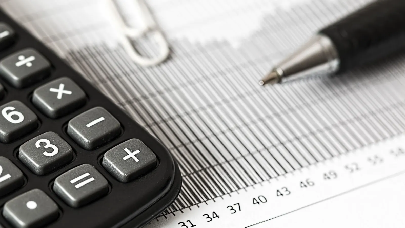 Kalkulator dan pulpen di atas kertas grafik