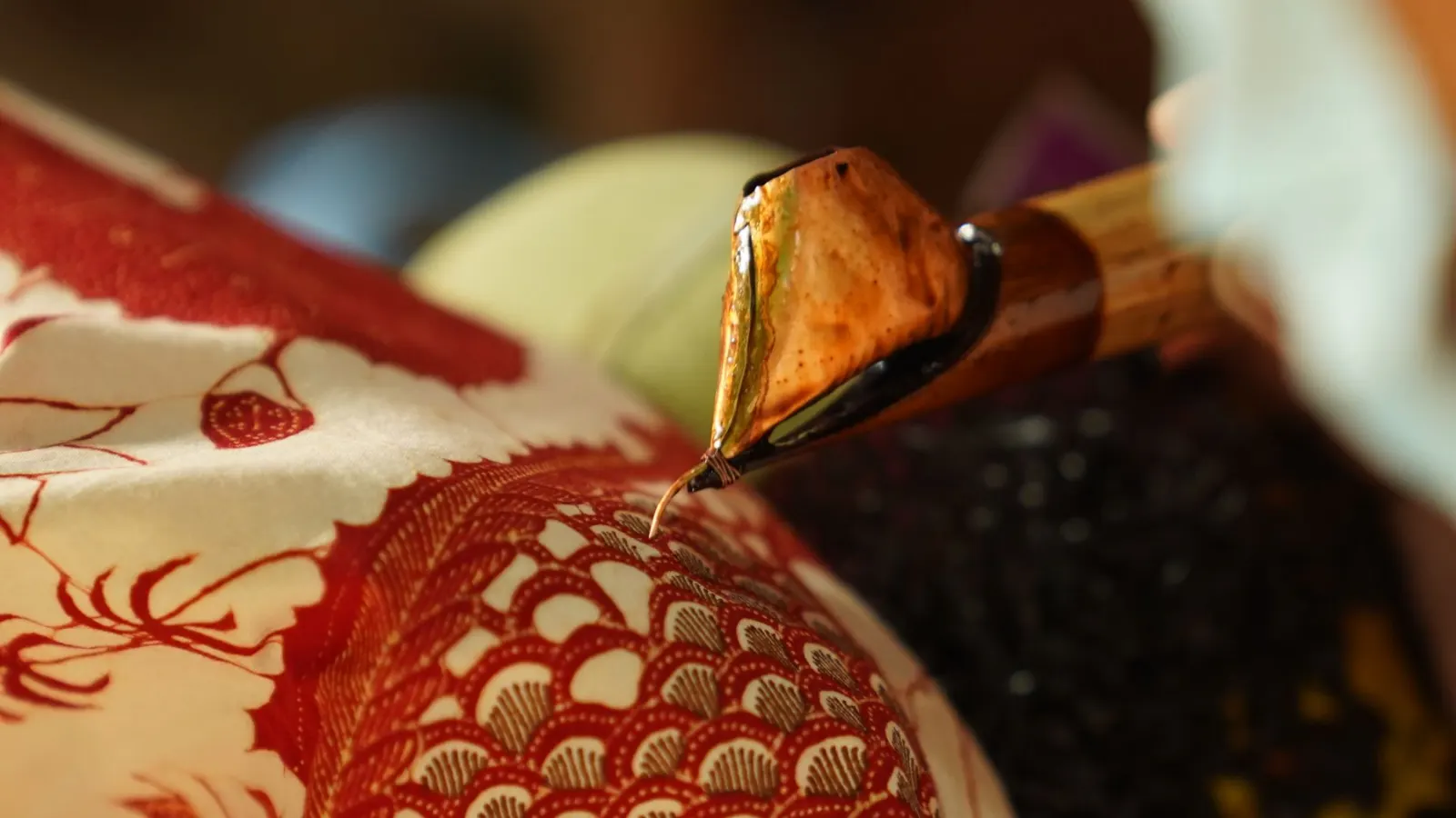 Canting menorehkan malam di kain batik
