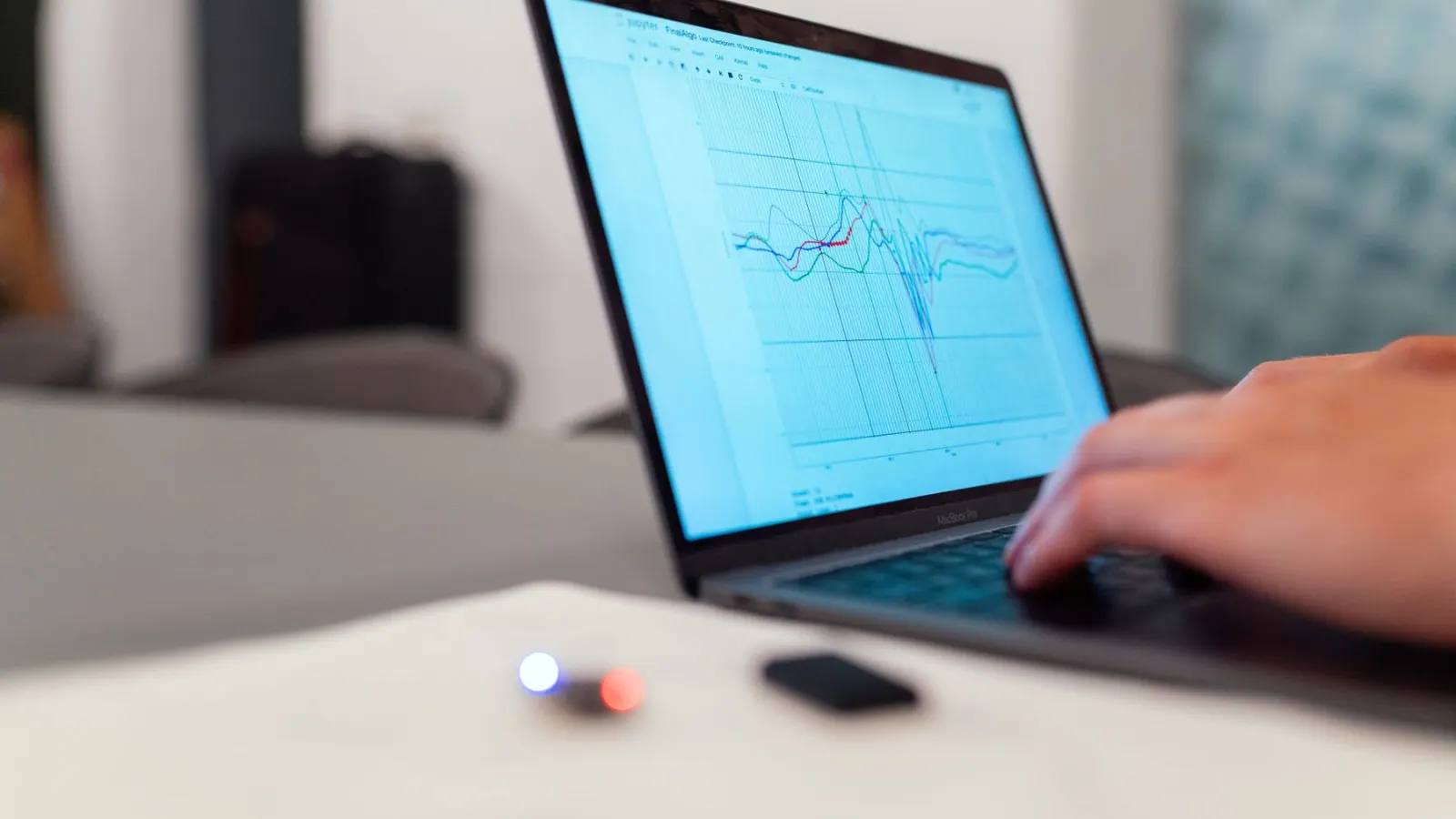 Tangan di laptop yang menampilkan grafik